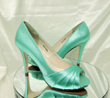 A pair of high heeled aqua blue satin shoes with a peep toe and a hidden platform at the front of the shoes