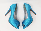 A pair of high heeled turquoise satin shoes with a peep toe and a hidden platform at the front of the shoes
