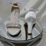 A pair of white block heel shoes with an ankle strap and a crystal design on the front toe strap of the shoes