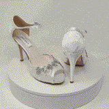 A pair of white high heeled platform lace shoes with an ankle strap and a crystal design on the front of the peep toe shoes