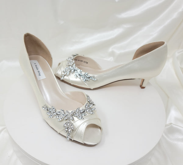 a pair of ivory low heels with a peep toe front and a crystal vine design across the front and side of the shoes