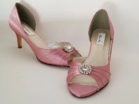 A pair of dusty rose medium height heel shoes with a peep toe and designed with a crystal design on the front of the shoes