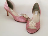 A pair of dusty rose satin medium height heel bridal shoes with a peep toe and designed with a crystal design on the front of the shoes