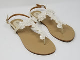 a pair of flat heel ivory bridal sandals with lace and pearls on the straps of the sandals