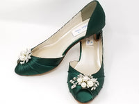 A pair of hunter green satin kitten heels with a peep toe and designed with a crystal and pearl design on the front of the shoes