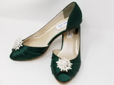 A pair of hunter green satin kitten heels with a peep toe and designed with a crystal design on the front of the shoes