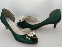 A pair of hunter green satin kitten heels with a peep toe and designed with a crystal and pearl design on the front of the shoes