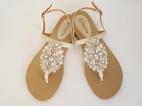 a pair of flat heel ivory bridal sandals with crystals on the straps of the sandals