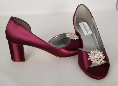 A pair of burgundy shoes with a low block heel and a peep toe front with a crystal design on the front of the shoes