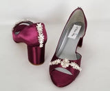 A pair of burgundy shoes with a low block heel and a peep toe front with a crystal and pearl design on the front of the shoes and a pearl and crystal design on the back of the shoes