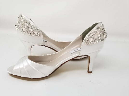 A pair of white satin bridal  heels with a peep toe and designed with a rose gold crystal design on the front of the shoes 