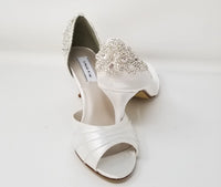 A pair of white satin wedding heels with a peep toe and designed with an all over lace design with pearls