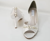 white bridal shoes with a medium heel height and a peep toe with a pearl and crystal design on the front of the shoes and the back heel of the shoes
