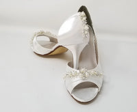 white bridal shoes with a medium heel height and a peep toe with a pearl and crystal design on the front of the shoes and the back heel of the shoes
