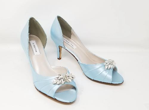 A pair of baby blue satin medium height heel shoes with a peep toe and designed with a crystal design on the front of the shoes