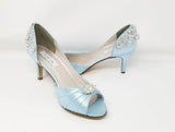 A pair of baby blue satin medium height heel shoes with a peep toe and designed with a crystal design on the front of the shoes and a crystal design on the back of the shoes heel