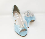 A pair of baby blue satin medium height heel shoes with a peep toe and designed with a crystal design on the front of the shoes and a crystal design on the back of the shoes heel