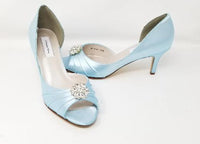 A pair of baby blue satin medium height heel shoes with a peep toe and designed with a crystal design on the front of the shoes