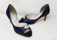 A pair of navy medium height heel shoes with a peep toe and designed with a crystal design on the front of the shoes