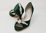 A pair of hunter green satin medium height heel bridal shoes with a peep toe and designed with a pearl and crystal design on the front of the shoes and a pearl and crystal design on the back heel of the shoes