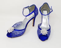 A pair of royal blue high heeled platform lace shoes with an ankle strap and a crystal design on the front of the peep toe shoes