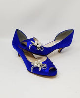 A pair of royal blue satin kitten heel shoes with a peep toe and a crystal and pearl design on the side of the shoes