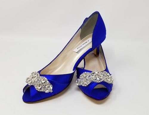 A pair of royal blue satin kitten heel shoes with a peep toe and a crystal design on the front of the shoes