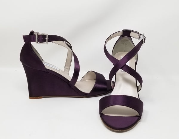 A pair of eggplant purple wedding shoes with high wedge and straps across the front of the foot 