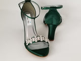 A pair of hunter green block heel shoes with an ankle strap and a crystal design on the front toe strap of the shoes