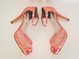 A pair of coral lace high heeled shoes with a front hidden platform and an ankle strap with a peep toe