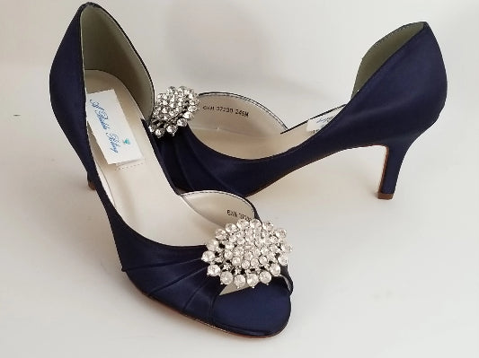 A pair of navy blue satin medium height heel shoes with a peep toe and designed with a crystal design on the front of the shoes