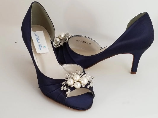 A pair of navy blue satin medium height heel shoes with a peep toe and designed with a pearl and crystal design on the front of the shoes