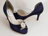 A pair of navy blue satin medium height heel shoes with a peep toe and designed with a crystal design on the front of the shoes