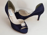 A pair of navy medium height heel shoes with a peep toe and designed with a crystal design on the front of the shoes
