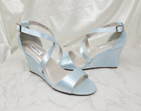 A pair of baby blue wedding shoes with high wedge and straps across the front of the foot 