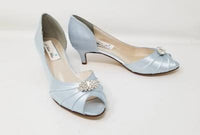 A pair of baby blue satin kitten heel shoes with a peep toe with a small crystal design on the front of the shoes