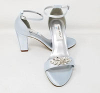 A pair of baby blue block heel shoes with an ankle strap and a crystal design on the front toe strap of the shoes