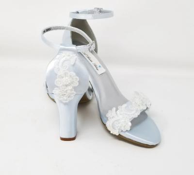 A pair of baby blue block heel shoes with an ankle strap and a lace and pearl design on the front toe strap of the shoes