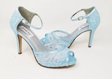 A pair of blue lace high heeled shoes with a front hidden platform and an ankle strap with a peep toe