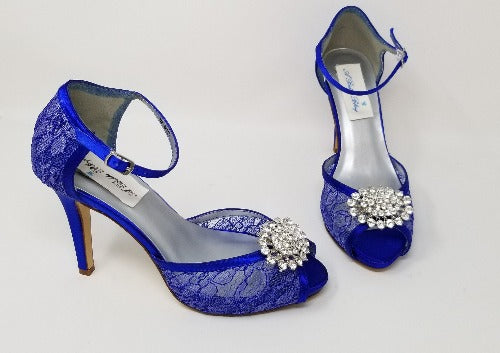A pair of royal blue high heeled platform lace shoes with an ankle strap and a crystal design on the front of the peep toe shoes