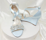 A pair of baby blue wedding shoes with high wedge and straps across the front of the foot designed with a crystal design on the front toe strap 