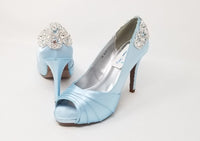 A pair of high heeled baby blue satin shoes with a peep toe and a hidden platform at the front of the shoes and a crystal design on the front of the shoes and a crystal design on the back heel of the shoes