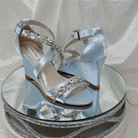 A pair of baby blue wedding shoes with high wedge and straps across the front of the foot designed with a crystal trim design across the straps
