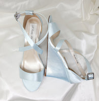 A pair of baby blue wedding shoes with high wedge and straps across the front of the foot 