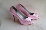A pair of high heeled pink satin shoes with a peep toe and a hidden platform at the front of the shoes 