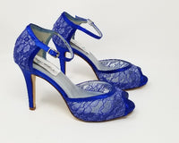 A pair of royal blue lace high heeled shoes with a front hidden platform and an ankle strap with a peep toe