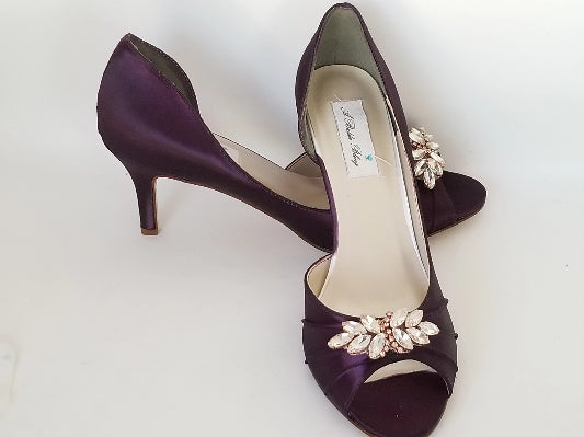 eggplant purple wedding shoes with peep toe and medium heel with a rose gold crystal design on the front of the shoes