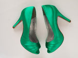 A pair of high heeled emerald green satin shoes with a peep toe and a hidden platform at the front of the shoes 