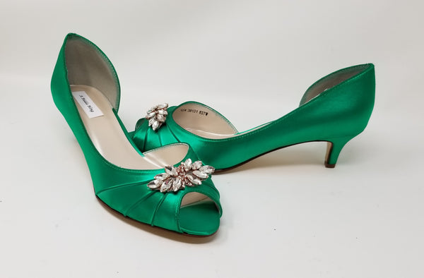A pair of emerald green satin kitten heels with a peep toe and designed with a rose gold crystal design on the front of the shoes