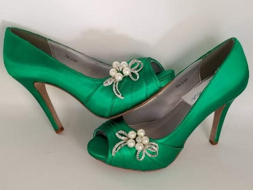 A pair of high heeled emerald green satin shoes with a peep toe and a hidden platform at the front of the shoes and a crystal and pearl design on the front of the shoes